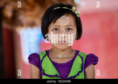 Birmano ragazza giovane indossando thanaka sul suo volto, polvere gialla che dà una sensazione di raffreddamento e fornisce la protezione dalle scottature, myanmar / BIRMANIA Foto Stock
