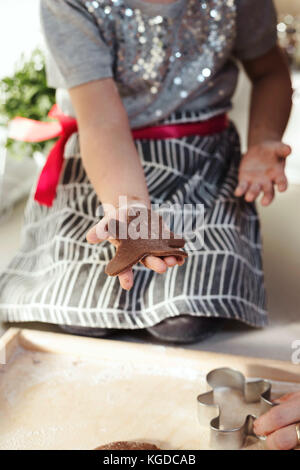 Anonimo bambino con le mani in mano il taglio di forme di festa al di fuori del panpepato pasta biscotto. Foto Stock