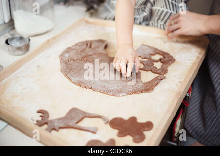 Anonimo bambino con le mani in mano il taglio di forme di festa al di fuori del panpepato pasta biscotto. Foto Stock