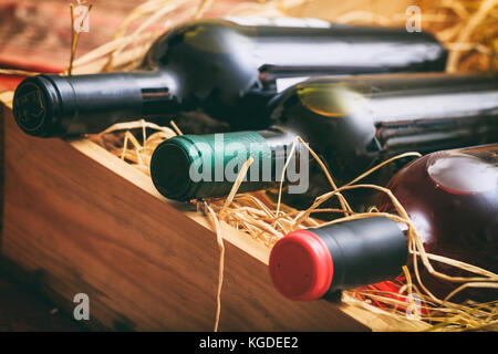 Rosso, rosa e bianco di bottiglie di vino sulla paglia, in una scatola di legno Foto Stock