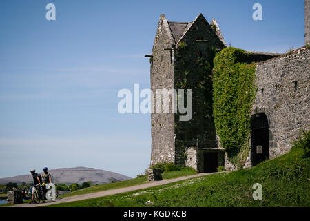 Ciclisti e turisti che visitano il castello di Dunguaire del XVI secolo sulla costa sud-orientale della baia di Galway nella contea di Galway, Irlanda, vicino a Kinvara. Foto Stock