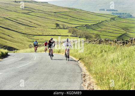 I ciclisti andare in bicicletta nelle valli dello Yorkshire Regno Unito viaggiando attraverso il bellissimo paesaggio vicino a Settle Foto Stock