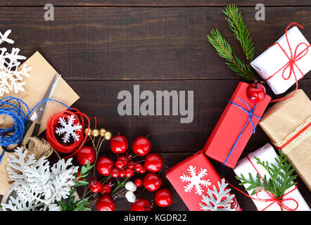 Anno nuovo, Natale. materiali decorativi, forbici, spago, carta, bacche, ramoscelli per la fabbricazione e la decorazione di confezioni regalo. Prodotto finito Foto Stock