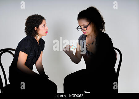 Facce illuminate come fortune Teller legge una giovane donna il futuro in una tazza di caffè Foto Stock