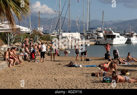 Agios Nikolaos, Creta, Grecia. I turisti sulla spiaggia municipale Ammos adiacente all'marina. Ottobre 2017 Foto Stock