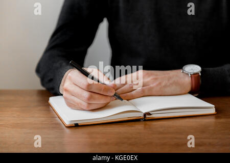 Lo stile di vita in stile minimalista di stock di foto di un uomo con una penna per scrivere nel notebook. Foto Stock