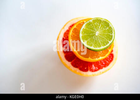 Pila colorati di metà di agrumi, vista superiore, orizzontale. pompelmo, arancione e calce semifrutti, sfondo bianco. Foto Stock