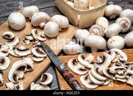Bianco fresco funghi su un sfondo di legno.gli champignon de paris tagliati a pezzi. Foto Stock