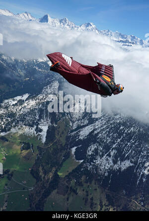 Wingsuit pilota è volare alto nel cielo sopra le Alpi. In tal modo il ponticello è volare gratis per un lungo periodo di tempo e con un grande sorriso sul suo volto. Foto Stock