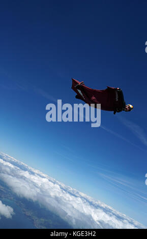 Wingsuit pilota è volare alto nel cielo sopra le Alpi. In tal modo il ponticello è volare gratis per un lungo periodo di tempo e con un grande sorriso sul suo volto. Foto Stock