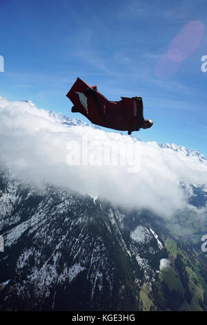 Wingsuit pilota è volare alto nel cielo sopra le Alpi. In tal modo il ponticello è volare gratis per un lungo periodo di tempo e con un grande sorriso sul suo volto. Foto Stock