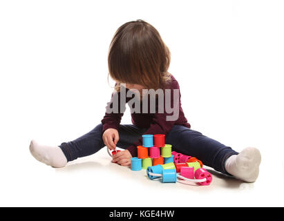 Due anni di ragazza che gioca con bobine di cotone in studio Foto Stock