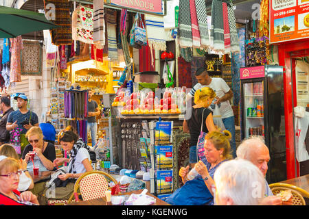 Israele la Terra Santa Gerusalemme città vecchia souk souk bazar mercato fresco bevande bancarella negozio tavoli sedie persone sciarpe Menorah cimeli turistici Foto Stock