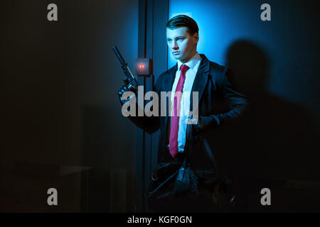 Professional l uomo è un omicida, in mano una pistola con un silenziatore. Foto Stock