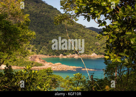 Spiaggia di Antigos e Antiguinhos. Una vista attraverso i boschi, la foresta incornicia la spiaggia. Acque cristalline. Paraty, Trindade, Rio de Janeiro, Brasile. Foto Stock