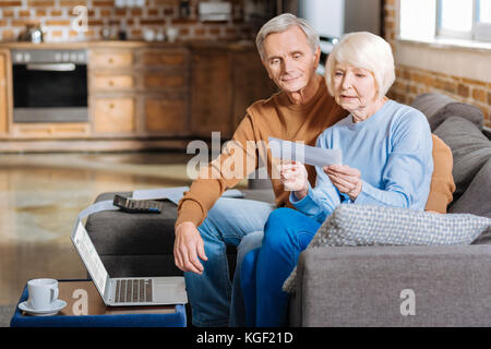 Grave donna anziana controllo documenti finanziari Foto Stock