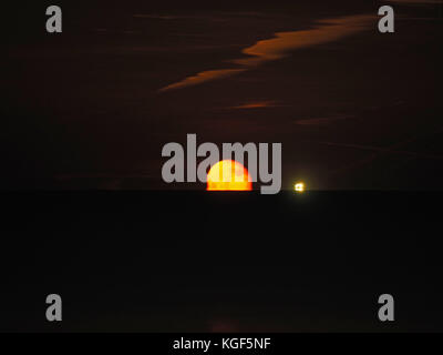 Sheerness, Kent, Regno Unito. 6 Nov, 2017. Regno Unito: Meteo sorgere della luna sopra l'estuario del Tamigi. La luna è apparso un cupo colore rosso come è salito sopra l'orizzonte. Il cluster di luci sono da una nave ancorata in estuario. Credito: James Bell/Alamy Live News Foto Stock