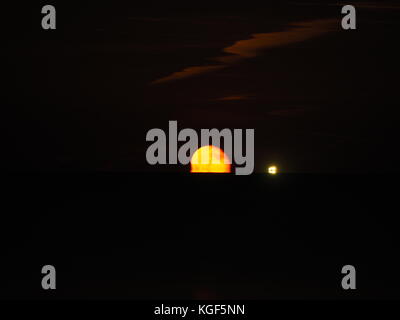 Sheerness, Kent, Regno Unito. 6 Nov, 2017. Regno Unito: Meteo sorgere della luna sopra l'estuario del Tamigi. La luna è apparso un cupo colore rosso come è salito sopra l'orizzonte. Il cluster di luci sono da una nave ancorata in estuario. Credito: James Bell/Alamy Live News Foto Stock