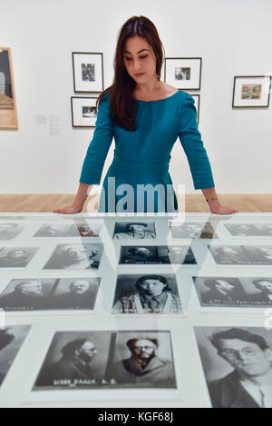 Londra, Regno Unito. 7 Nov, 2017. Un membro del personale viste mugshots prigione presso un'anteprima di "stella rossa sulla Russia: Una rivoluzione nella cultura visiva 1905-55' alla Tate Modern. La mostra celebra il centenario della Rivoluzione di Ottobre e presenta la storia visiva della Russia e Unione Sovietica con opere tratte principalmente dalla collezione del compianto graphic designer David King. Credito: Stephen Chung/Alamy Live News Foto Stock