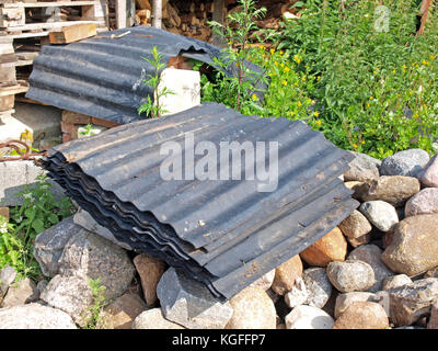 Vecchio usato in gomma nera tegole del tetto sventolato realizzato da pneumatici riciclati outdoor impilati su pietre. Foto Stock