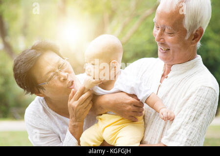 Nonni prendersi cura della nipote nel parco all'aperto. famiglia asiatica, assicurazione vita concetto. Foto Stock