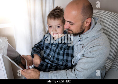 Padre e figlio giocare con tavoletta digitale Foto Stock