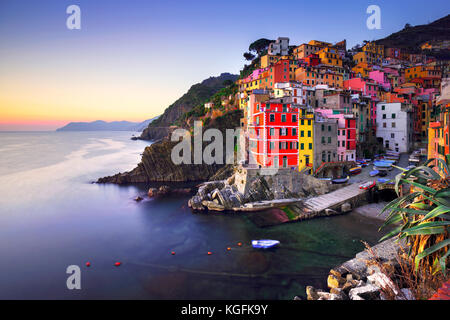 Riomaggiore villaggio sulla scogliera di rocce e mare al tramonto., Seascape in cinque terre, il Parco Nazionale delle Cinque Terre Liguria Italia Europa. Esposizione lunga Foto Stock