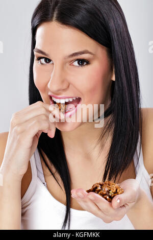 Mangiare sano, giovane donna mangiare noci sgusciate Foto Stock