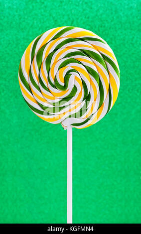 Spirale rotonda lollipop su un lucido verde glitter sfondo Foto Stock