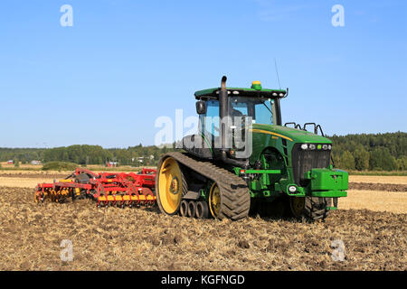 Salo, Finlandia - agosto 21, 2015: unnamed contadino coltiva il campo con John Deere 8345RT trattore cingolato e Coltivatore Vaderstad da coltivatore a impostazione di Foto Stock