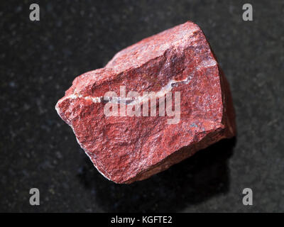 Le riprese in modalità macro di minerale naturale campione di roccia - Materie di diaspro rosso sulla pietra di granito scuro dello sfondo Foto Stock