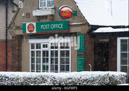 Freddo, nevoso inverno scena con esterno del villaggio Post Office visto attraverso la caduta di fiocchi di neve - Menston, West Yorkshire, Inghilterra, Regno Unito. Foto Stock