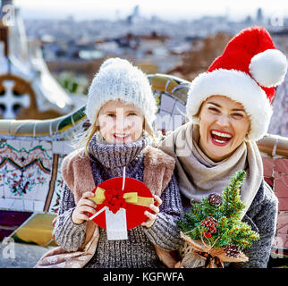 Winter Wonderland di Barcellona a Natale. ritratto di felice alla moda di madre e bambino i turisti con un piccolo albero di natale e la presente casella al guell Foto Stock