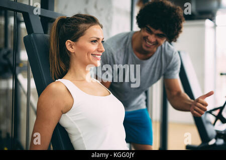 Giovane bella donna facendo esercizi con personal trainer Foto Stock