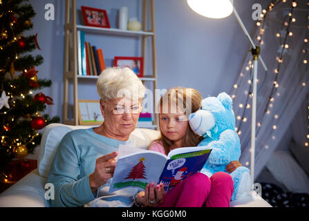 Serata di natale con la nonna, storybook e orsacchiotto Foto Stock