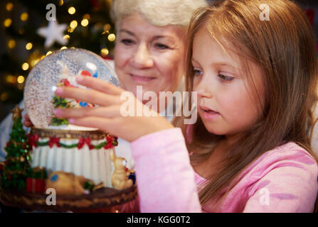 Senior con ragazza a guardare il natale Snow Globe Foto Stock