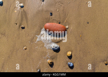 Ciottoli e pietre di rendere attraenti modelli nella sabbia sulla spiaggia Seaham come la marea si ritira, County Durham, Regno Unito Foto Stock