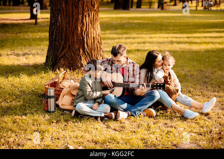 Famiglia su picnic a suonare la chitarra Foto Stock