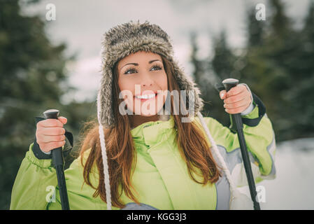 Ritratto di una giovane e bella donna godendo di vacanze di sci. ella in piedi con gli sci e guardando lontano con il sorriso. Foto Stock