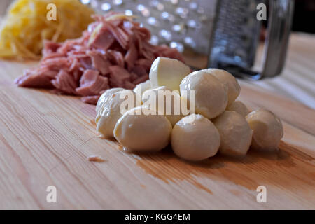 Il formaggio grattugiato e il prosciutto tritato, palline di mozzarella e grattugia su sfondo di legno Foto Stock