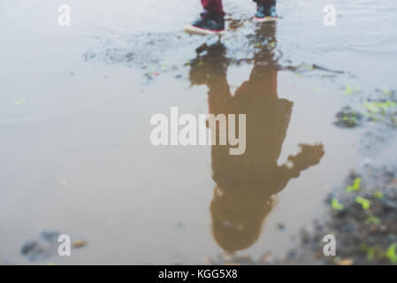 Bambino a camminare in una pozza di fango Foto Stock