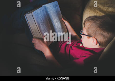 10-11 anno vecchio ragazzo la lettura di un libro Foto Stock