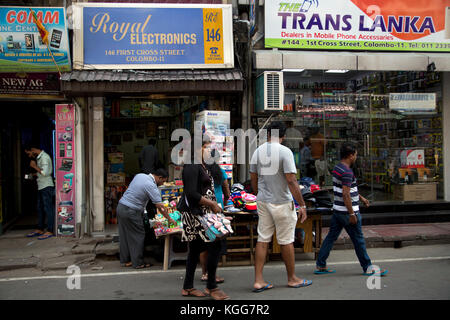 Il Pettah Colombo Sri Lanka primo Cross Street persone guardando cappelli su pressione di stallo fuori Royal Electronics shop Foto Stock