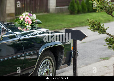 Dettaglio del nero lussuoso ed elegante auto nozze decorativa con un tabella che mostra direzione parcheggiato su una strada Foto Stock