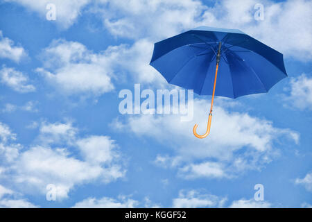 Ombrello blu vola in cielo contro di nuvole bianche.vento di cambiamento concetto.Mary Poppins ombrello. Foto Stock