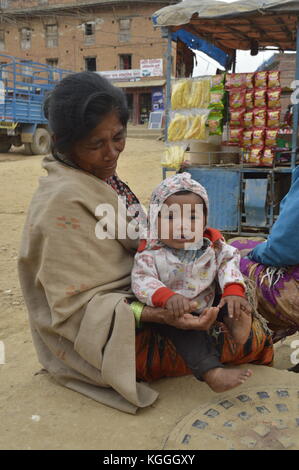 Vecchia nonna nepalese con nipote in grembo. tenendo mani e piedi. A Panauti, Nepal. bambino. bei occhi marroni. Foto Stock