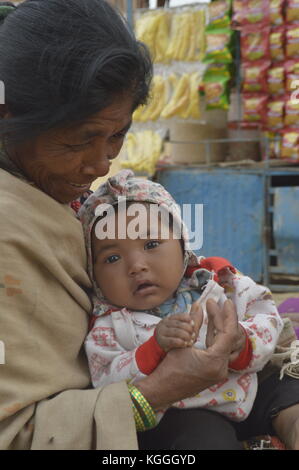 Vecchia nonna nepalese con nipote in grembo. tenendo mani e piedi. A Panauti, Nepal. bambino. bei occhi marroni. Foto Stock