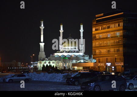 Una moschea moderna in un Kazakhstan musulmano nella capitale Almaty durante la notte, ben illuminato, buio. inverno, neve ghiacciata molto alta. Foto Stock