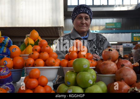 Mercato al coperto / bazar ad almaty, kazakhstan. Una donna kazaka e un uomo vendono cibo in bazaar. mandarini, noci, frutta secca, mele Foto Stock