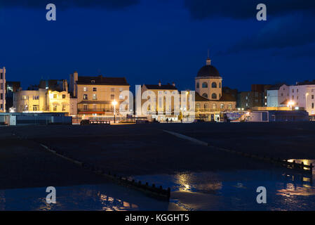 Edifici adiacenti al molo, tra cui il Dome Theatre, sul lungomare di Worthing illuminato a novembre sera poco dopo il tramonto Foto Stock